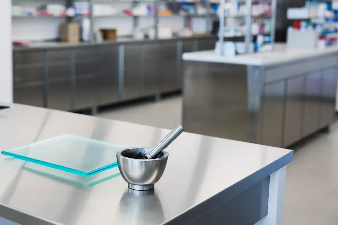 A pharmacy compounding bench with a mortar and pestle and a glass slab