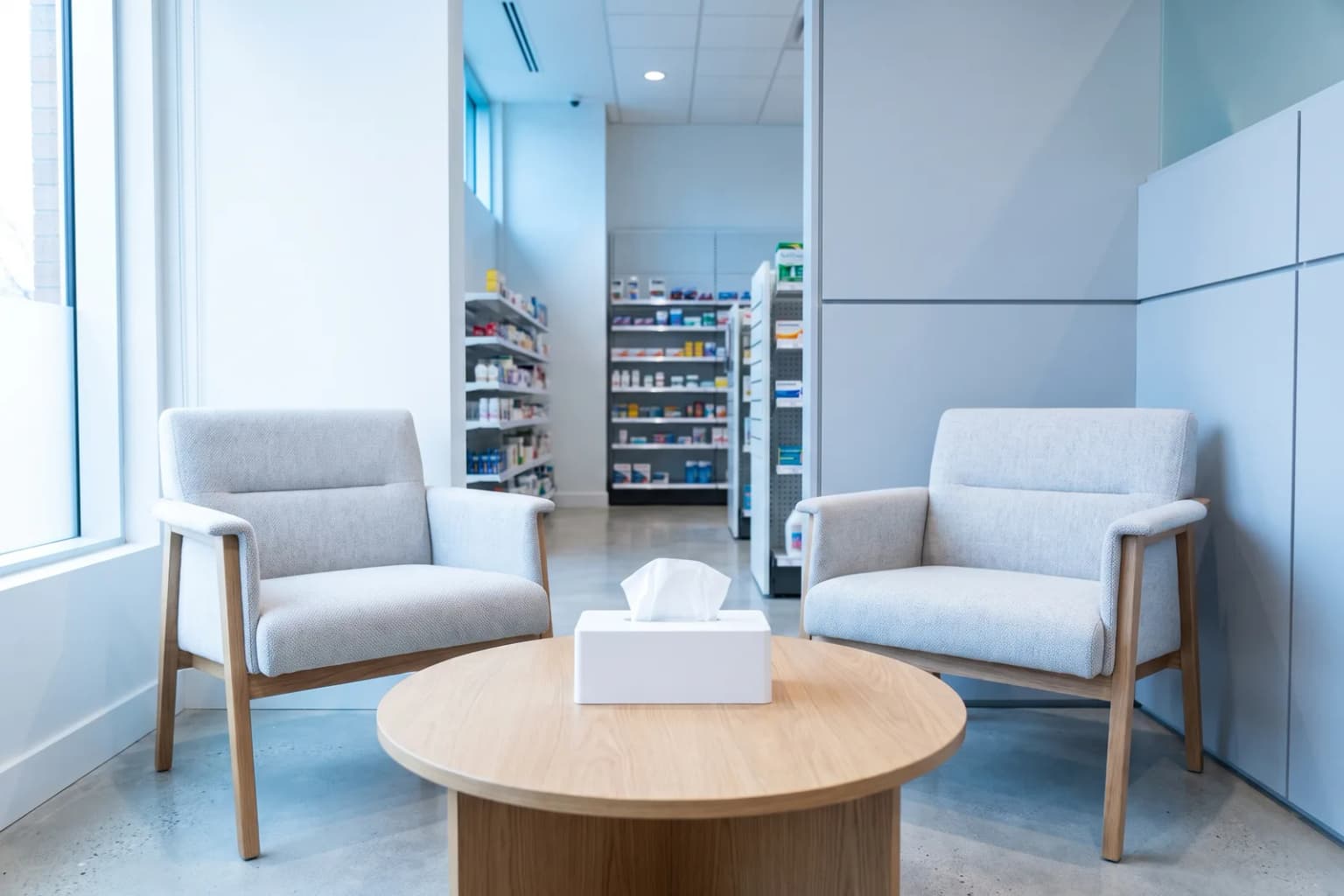 A quiet consultation corner with two chairs, pharmacy shelving beyond