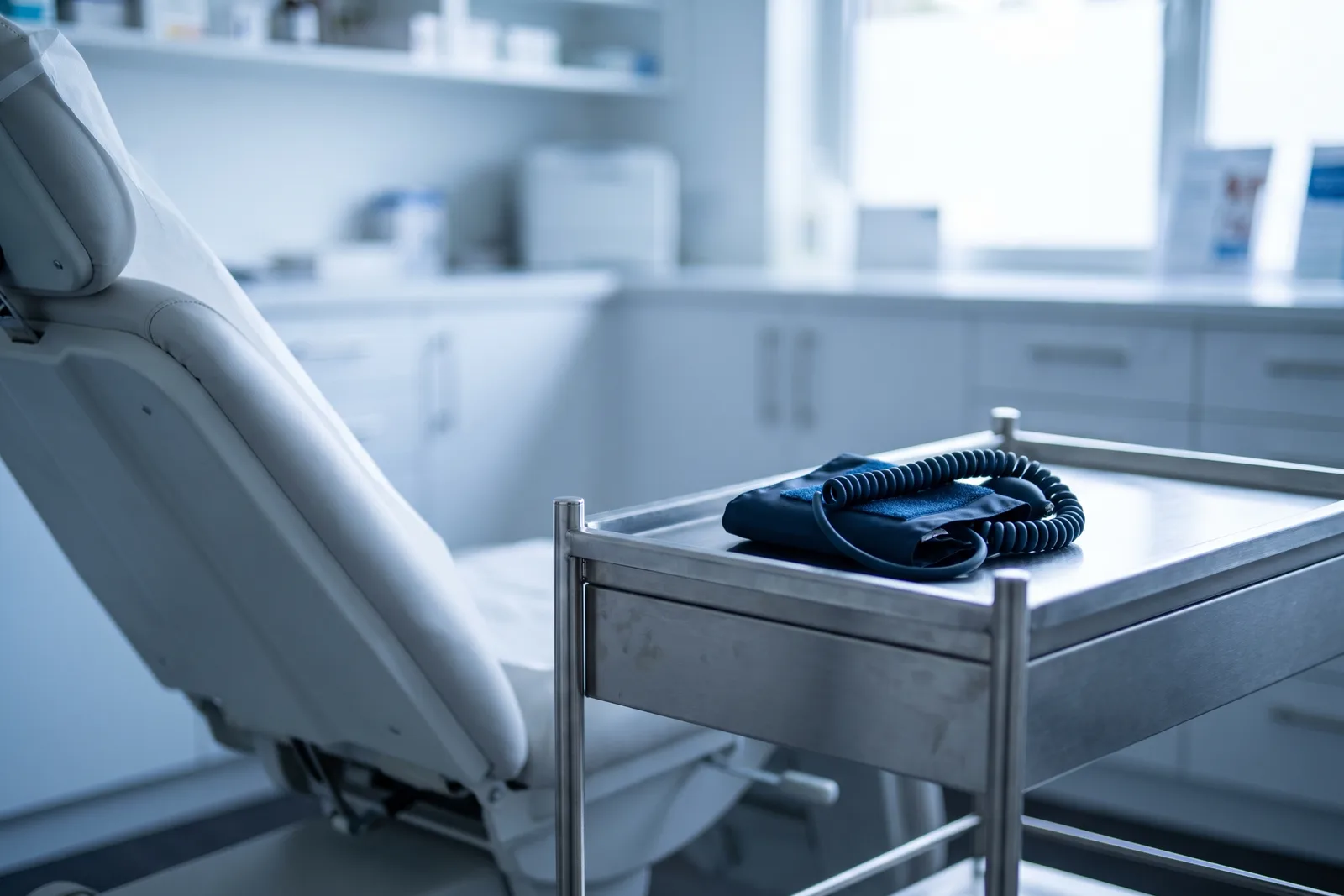 An examination chair beside a steel trolley holding a blood-pressure cuff